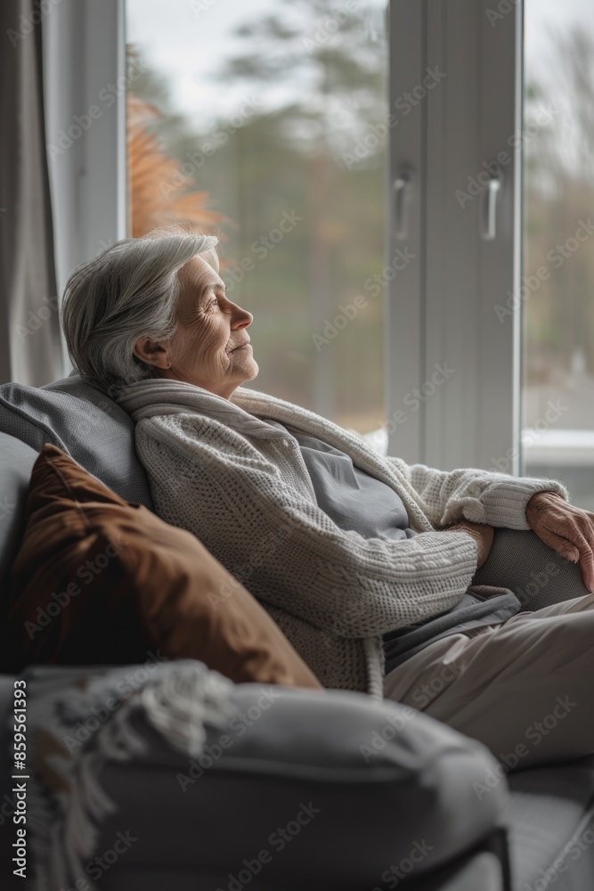 A person sitting on a couch with a view of the outdoors, possibly contemplating or daydreaming A person sitting on a couch with a view of the outdoors, possibly contemplating or daydreaming