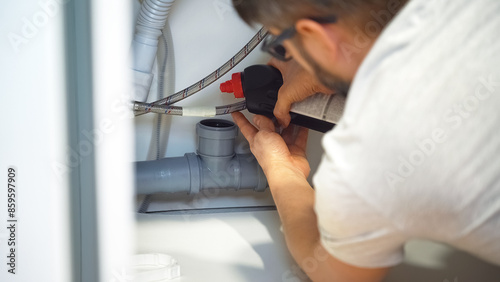Plumber hands pour remedy for blockage of sewer pipes in kitchen sink. Removing blockage clog in drain pipe. Sewer blockage