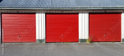red garage doors on a line with white walls and old metal roofing