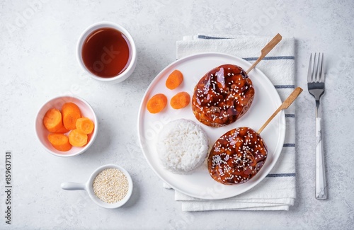 Tsukune, Japanese Chicken Meatball in teriyaki sauce with sesame seeds sprinkles with rice and vegetables in a plate photo