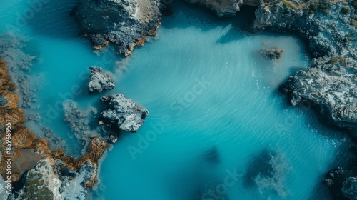 A stunning aerial shot showcasing the contrast between vibrant turquoise waters and rugged rocky formations along the coast, highlighting nature's beauty and serenity. photo
