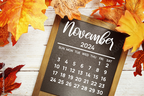 November 2024 monthly calendar maple leaf decoration on wooden background photo