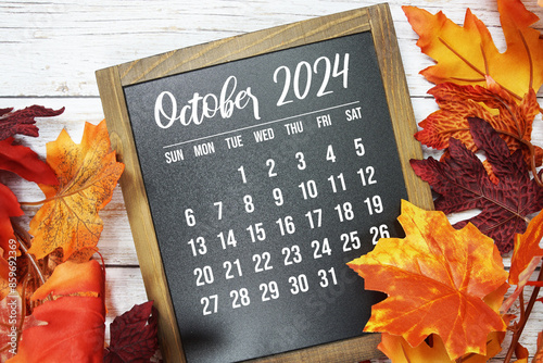 October 2024 monthly calendar maple leaf decoration on wooden background photo