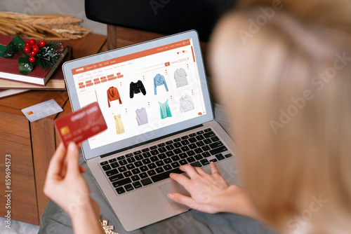 Young woman using laptop with credit card for internet banking, online shopping E commerce by online payment gateway at home. Modern and convenience online shopping with debit card. Blithe photo