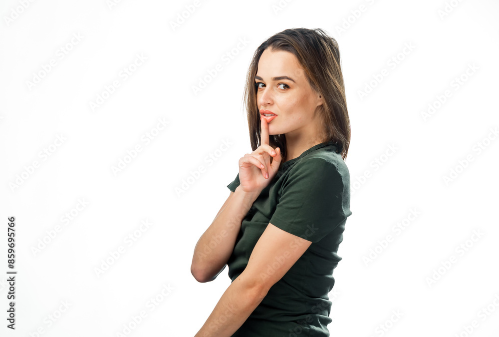 Woman Holding Finger To Lips. A woman with brown hair is shown with her finger to her lips, looking at the camera with a mischievous smile. Woman Holding Finger To Lips. A woman with brown hair is shown with her finger to her lips, looking at the camera with a mischievous smile.