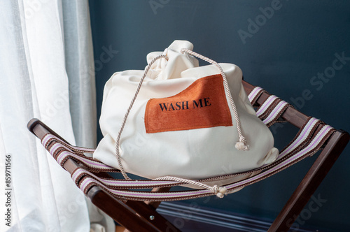 white laundry bag on chair with dark background with text 'wash me'