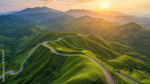 Rolling mountain highway snaking through verdant hills under a radiant golden sunrise. photo