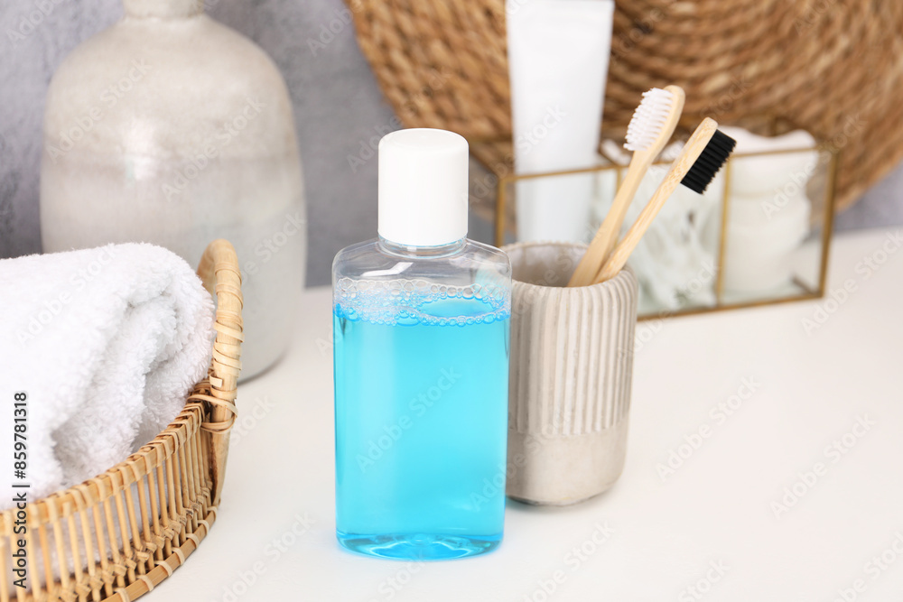 Bottle of mouthwash and toothbrushes on white table in bathroom Bottle of mouthwash and toothbrushes on white table in bathroom