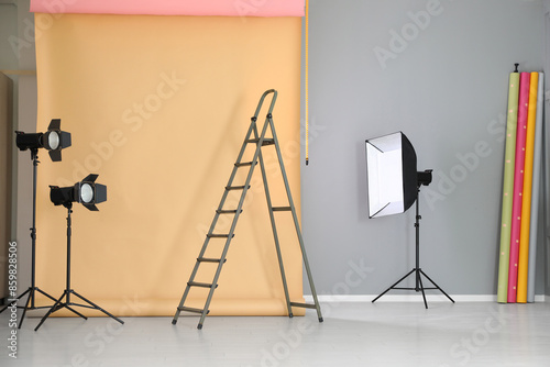 Pale orange photo background and professional lighting equipment in modern studio