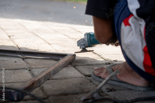 Person using angle grinder to cut metal frame