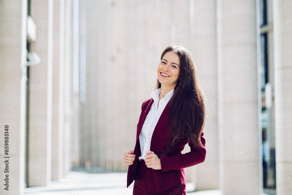 confident businesswoman in a burgundy suit standing and smiling in a modern urban setting confident businesswoman in a burgundy suit standing and smiling in a modern urban setting
