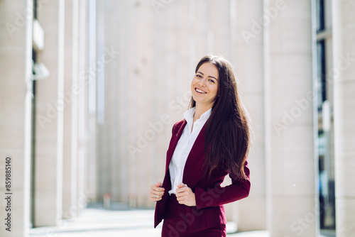 Free Download confident businesswoman in a burgundy suit standing and smiling in a modern urban setting - GFXLoad