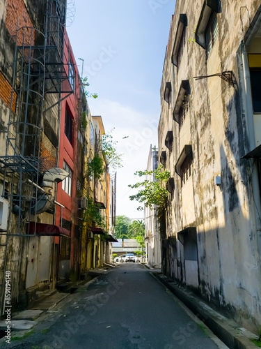 Road path in between two rustic building with green tropical bushes. photo