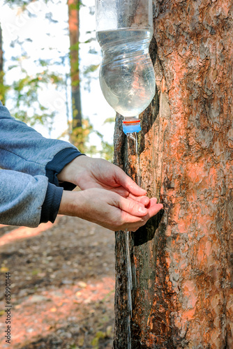 A tourist washes their hands at a camping wash basin made from a plastic water bottle.