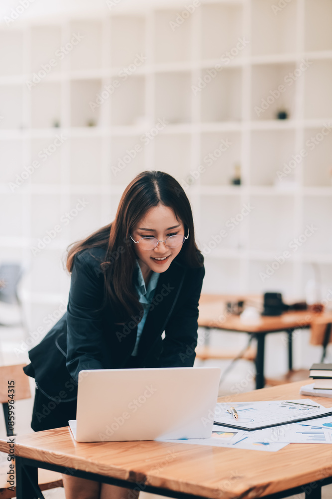 Happy young asian businesswoman sitting on her workplace in the office. Young woman working at laptop in the office. Happy young asian businesswoman sitting on her workplace in the office. Young woman working at laptop in the office.