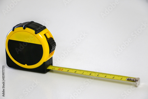 Black and yellow retractable tape measure against white background photo