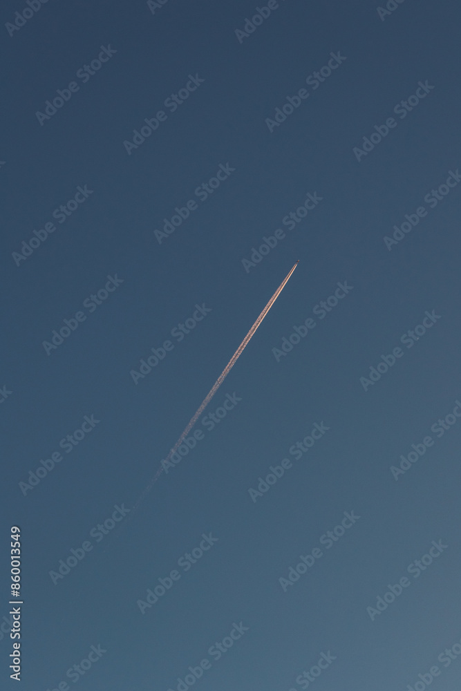 Airplane's trajectory against a cloudless sunset sky, creating a striking visual against the colorful horizon Airplane's trajectory against a cloudless sunset sky, creating a striking visual against the colorful horizon
