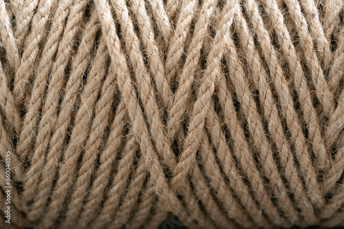 Tightly wound coil of natural fiber rope, displaying its robust texture and earthy beige color. Organic appearance make it ideal for backgrounds, crafts, and eco-friendly projects.