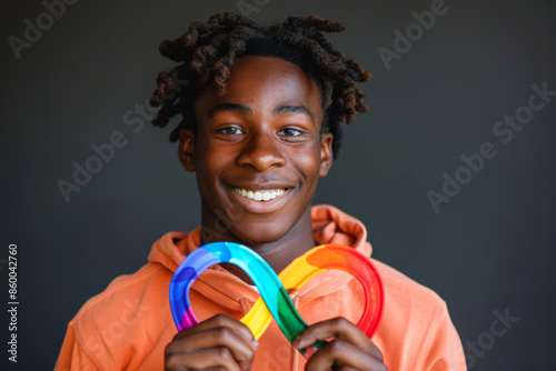 Сoncept of neurodiversity. Neurological differences in society. Portrait of a smiling young adult holding a colorful rainbow infinity sign