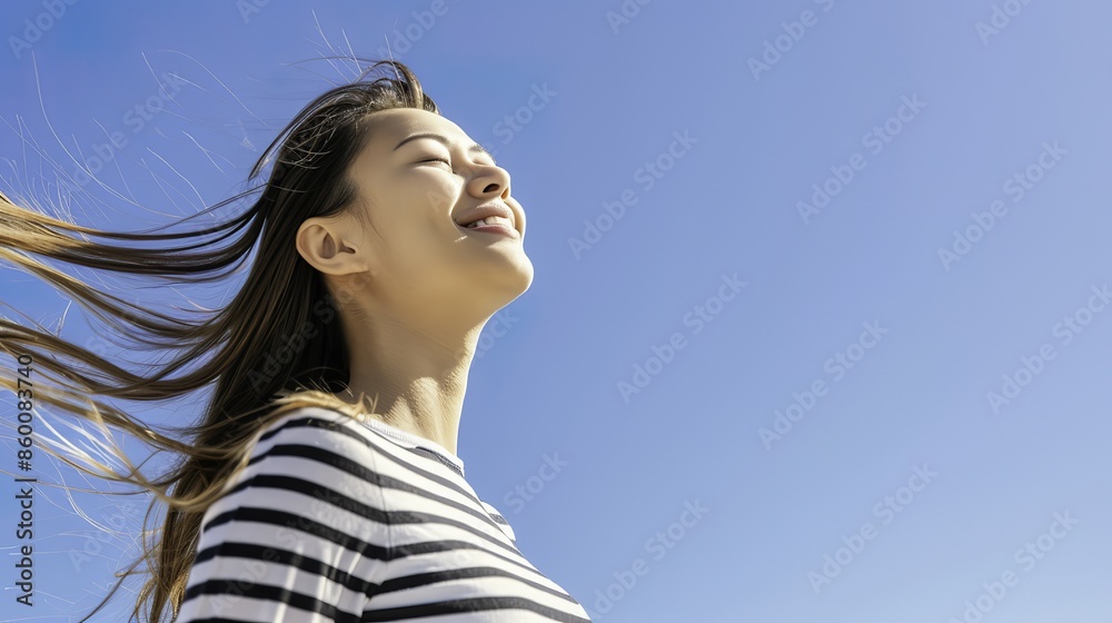 Serene young Asian woman with closed eyes standing under clear blue sky Serene young Asian woman with closed eyes standing under clear blue sky