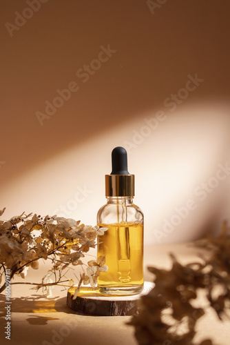 Dropper bottle on wooden podium with dry flowers on pastel beige background. Aesthetic, minimal beauty product packaging design.