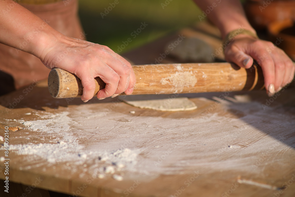 A person is rolling out dough on a wooden table A person is rolling out dough on a wooden table
