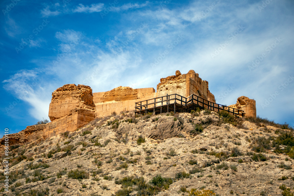 View of the ruins of the medieval castle of Pliego, Murcia Region, Spain, on a steep, rocky hill and blue sky
View of the ruins of the medieval castle of Pliego, Murcia Region, Spain, on a steep, rocky hill and blue sky