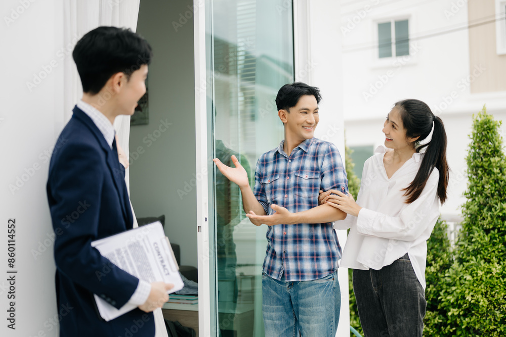Asian man Real estate broker agent showing a house detail in her file to the young Asian couple lover looking and interest to buy it. Asian man Real estate broker agent showing a house detail in her file to the young Asian couple lover looking and interest to buy it.