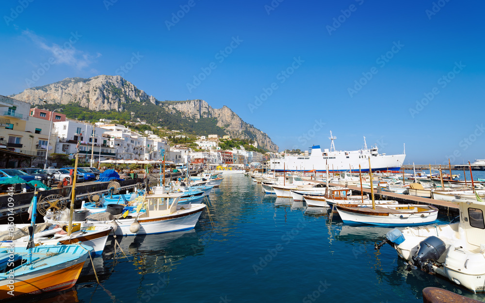 Welcome to Capri concept image. Morning view of Marina Grande in Capri, Italy, showcases serene turquoise waters, boats and picturesque coastal buildings under clear blue sky Welcome to Capri concept image. Morning view of Marina Grande in Capri, Italy, showcases serene turquoise waters, boats and picturesque coastal buildings under clear blue sky