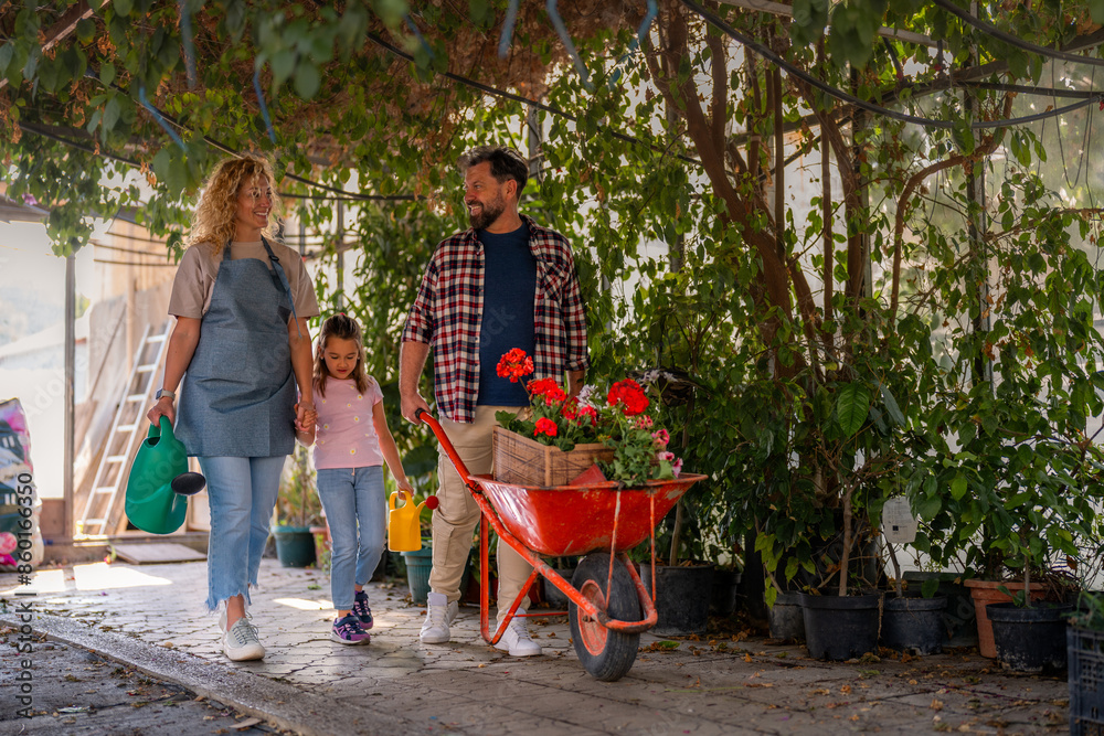 A family walking into a greenhouse, pushing a wheelbarrow filled with colorful flowers and chatting happily. A family walking into a greenhouse, pushing a wheelbarrow filled with colorful flowers and chatting happily.
