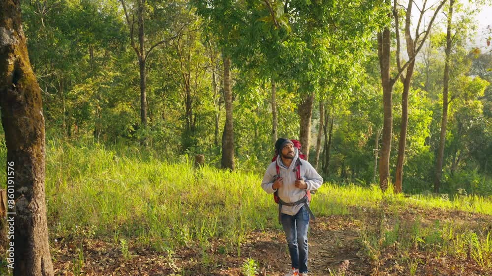 Indian man backpacker hiking in tropical forest on summer holiday vacation. Handsome guy traveler enjoy outdoor active lifestyle walking on mountain dirt road. Ecotourism and solo travel concept. Indian man backpacker hiking in tropical forest on summer holiday vacation. Handsome guy traveler enjoy outdoor active lifestyle walking on mountain dirt road. Ecotourism and solo travel concept.