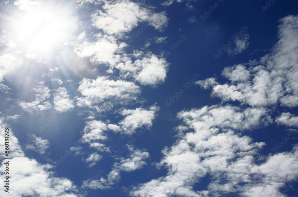 Obraz premium Bright light of the sun on a dark blue sky among the clouds.