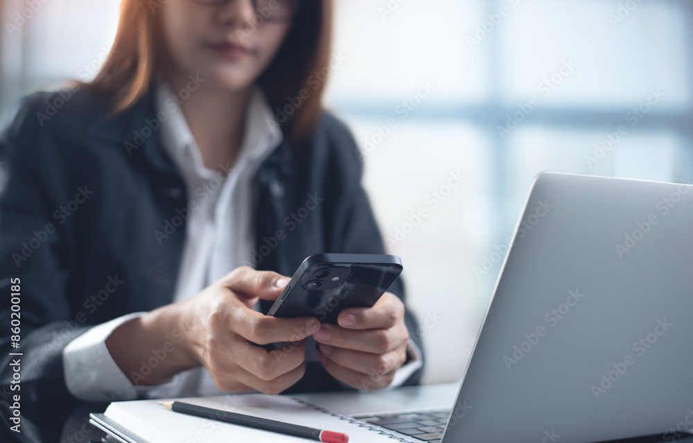 Young smart businesswoman using mobile phone, working on laptop computer at modern office. Asian business woman using smartphone searching the information, surfing the internet Young smart businesswoman using mobile phone, working on laptop computer at modern office. Asian business woman using smartphone searching the information, surfing the internet
