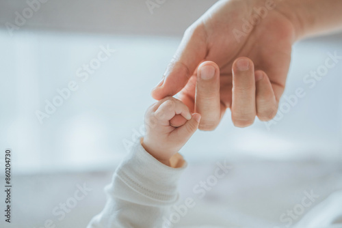 Close-up little hand of child baby holding hand of mother, A newborn holds on to mom's, dad's finger, Love and relationship with infant, Care and support, Dreaming and protection