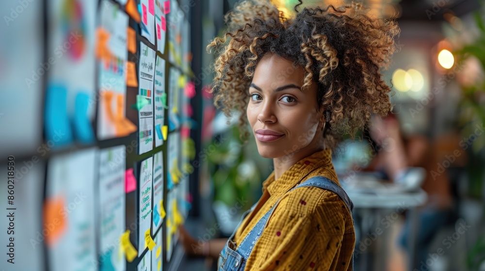 Creative Professional with Sticky Notes. Creative professional woman with curly hair stands by a wall covered in colorful sticky notes, brainstorming ideas.