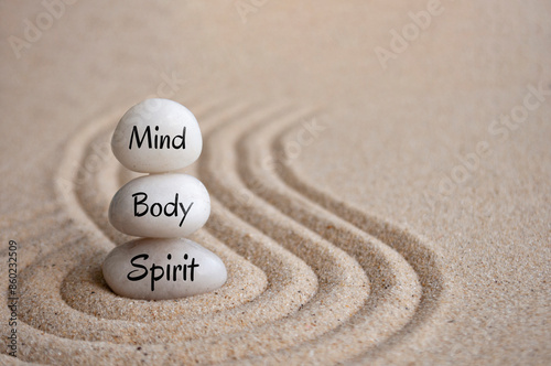 Mind, body and spirit text on Zen stones on sand background photo