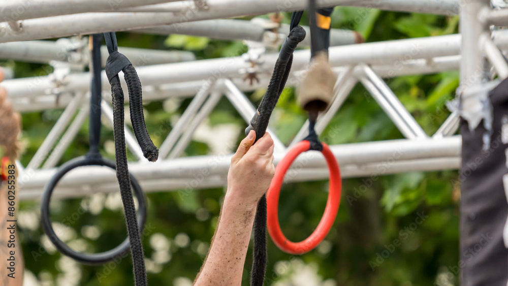 Hands grasp a rope at a hanging obstacle in an obstacle course