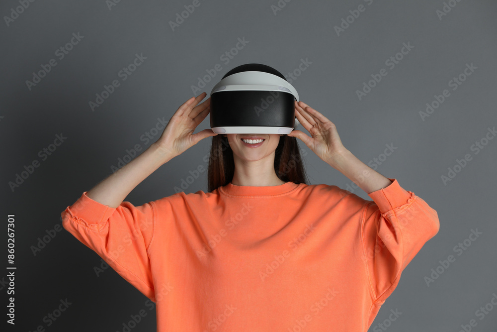 Smiling woman using virtual reality headset on gray background Smiling woman using virtual reality headset on gray background