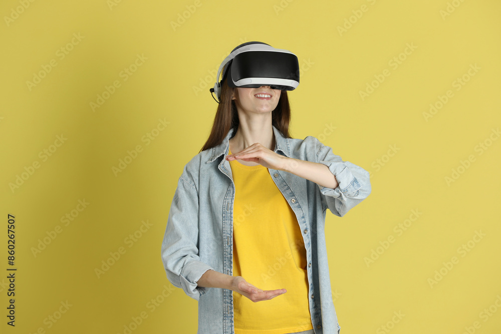 Smiling woman using virtual reality headset on yellow background Smiling woman using virtual reality headset on yellow background