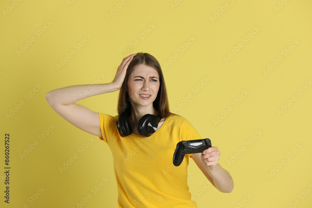 Unhappy woman with controller on yellow background Unhappy woman with controller on yellow background