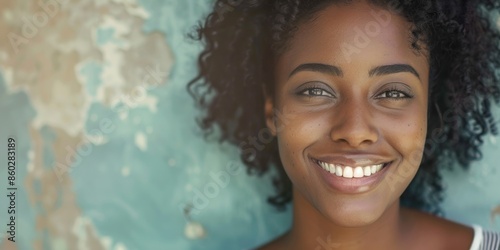 A woman with curly hair smiling directly at the camera, a simple and cheerful expression