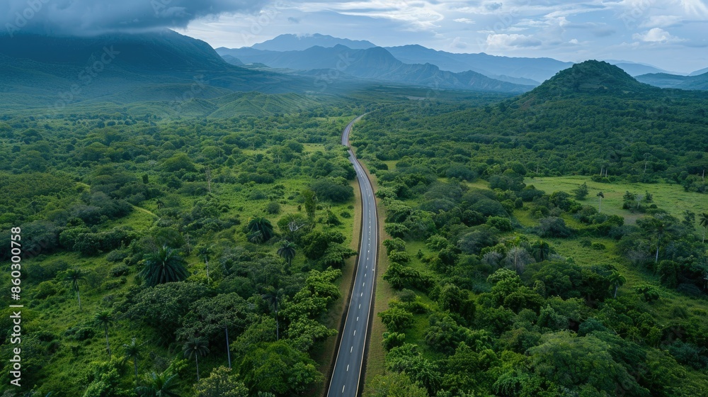 Fototapeta premium Aerial view of countryside asphalt road amidst green forest and mountains