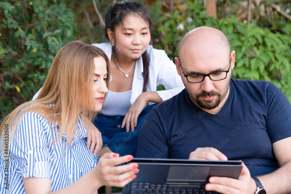 Happy young multiethnic couple spending time together at the park, studying while with laptop Happy young multiethnic couple spending time together at the park, studying while with laptop