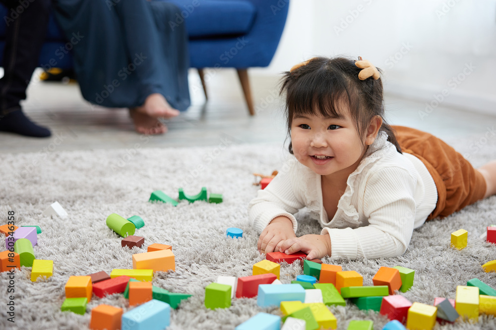 child girl feeling happy and playing with colorful toy blocks on the carpet floor child girl feeling happy and playing with colorful toy blocks on the carpet floor