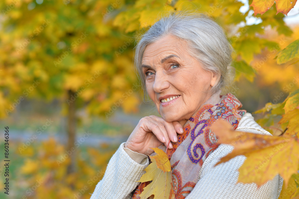 Senior nice woman walking in the park in autumn.
