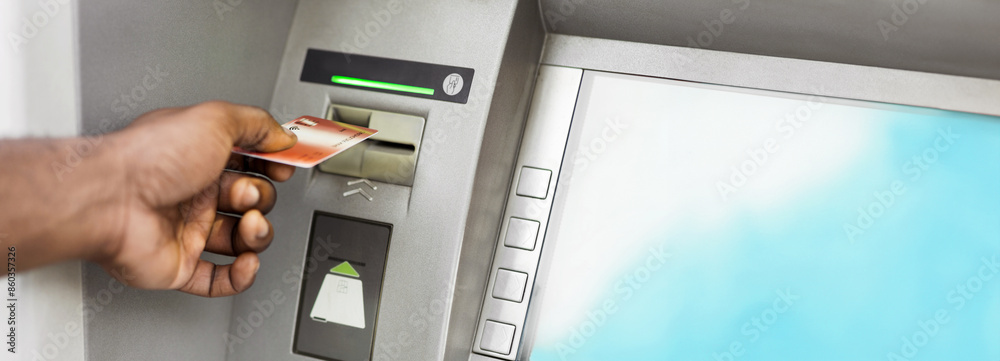 Close up of black man using ATM with gold credit card, panorama, copy space Close up of black man using ATM with gold credit card, panorama, copy space