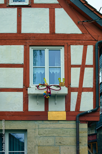 Close-up view of stone facade with one window and flower pot with blooming flowers. Typical architecture in Kronach town, Bavaria, region Upper Franconia, Germany. Travel and tourism concept
