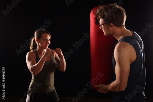 junges Pärchen beim Boxtraining, er hält den Boxsack, schwarzer Hintergrund photo