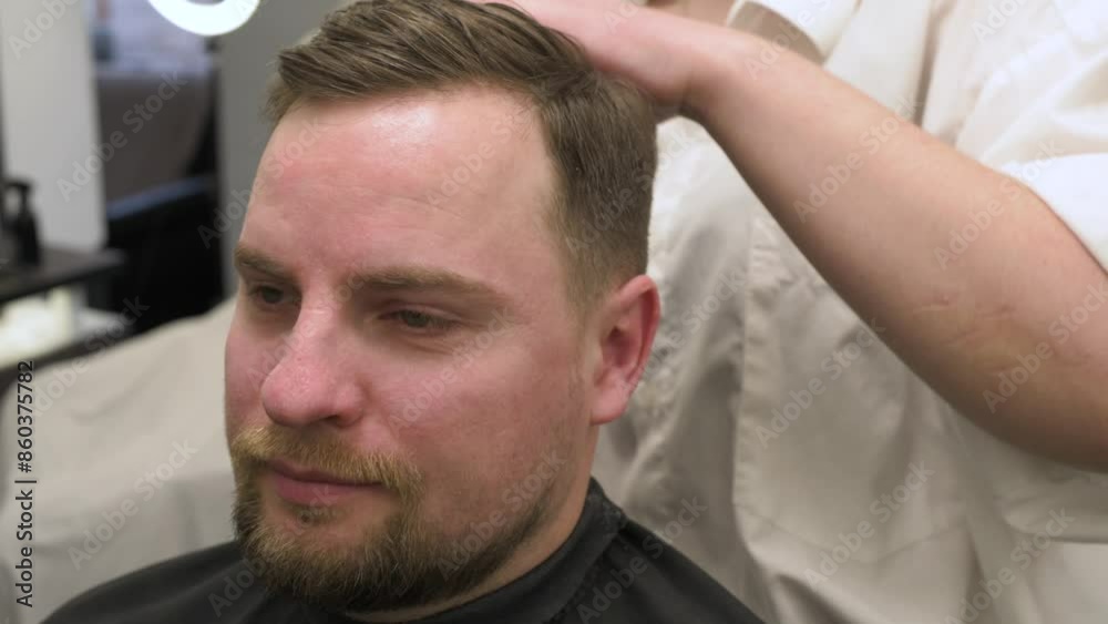 Haircut of a visitor in a barbershop. Hair styling with a hand, combing the client's hair by a stylist. Haircut of a visitor in a barbershop. Hair styling with a hand, combing the client's hair by a stylist.