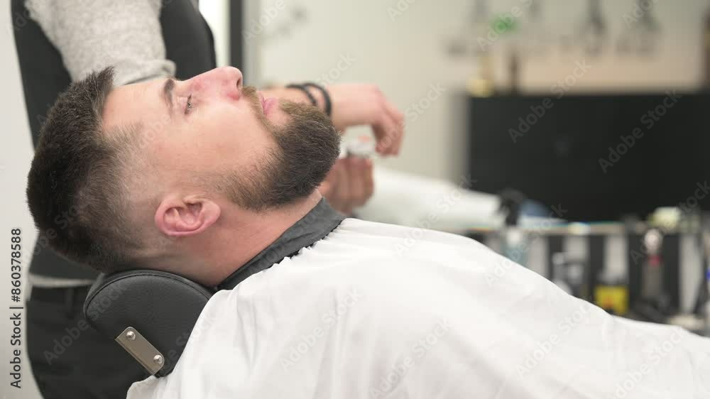 Beard cut of a visitor in a barbershop. Styling a beard with a hand, combing the client's hair by a stylist.